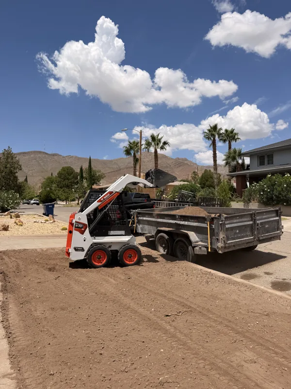 Bobcat S70 grading a dirt lot with the dump trailer alongside